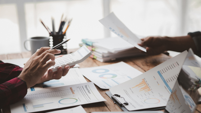 rokas ar kalkulatoru un dokumentiem