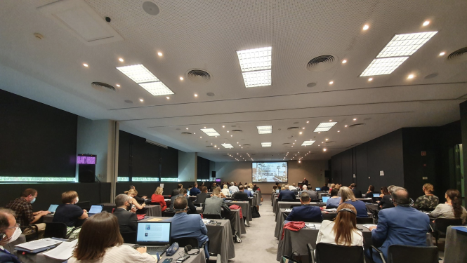 Konferences dalībnieki zālē klausās uzrunu