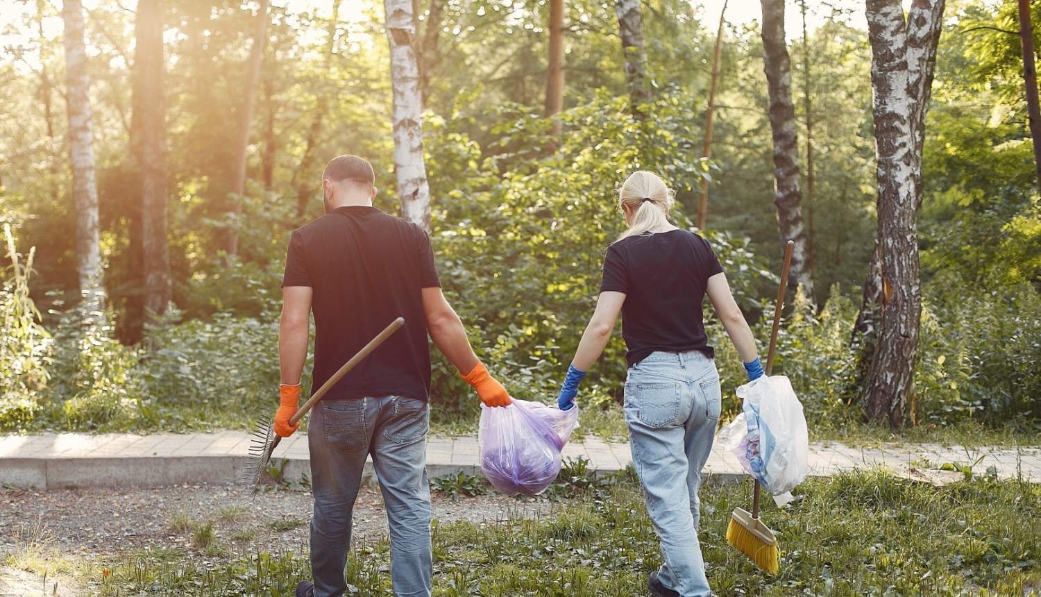 divi cilvēki nes atkritumu maisu un darba instrumentus