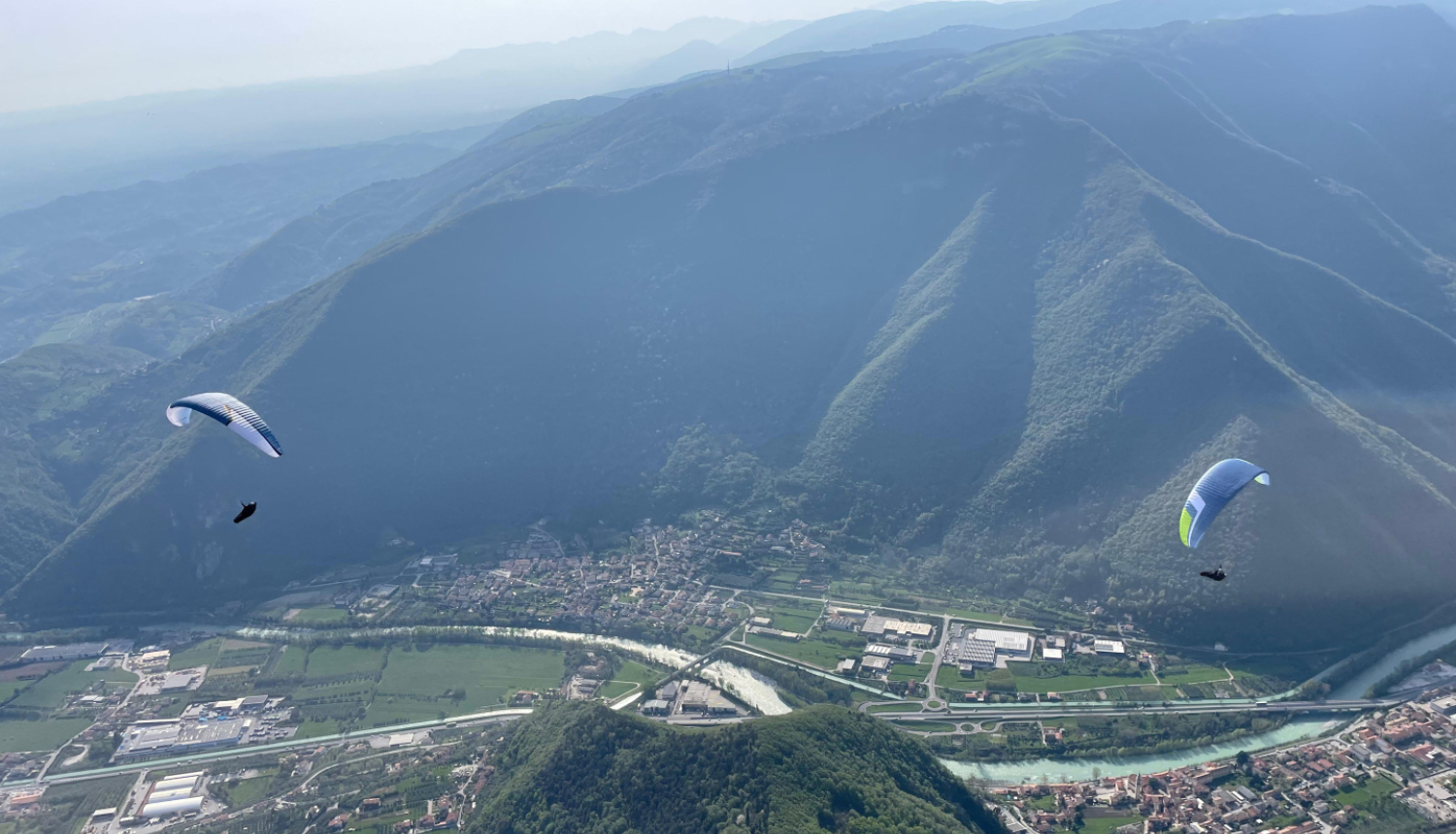 divi paraplāni lido virs ielejas starp kalniem