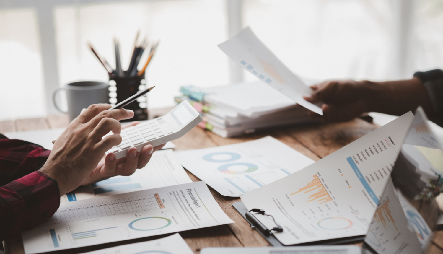 rokas ar kalkulatoru un dokumentiem