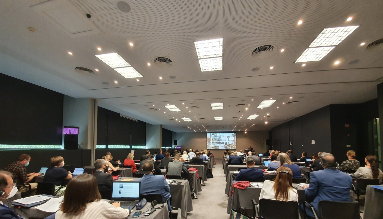 Konferences dalībnieki zālē klausās uzrunu