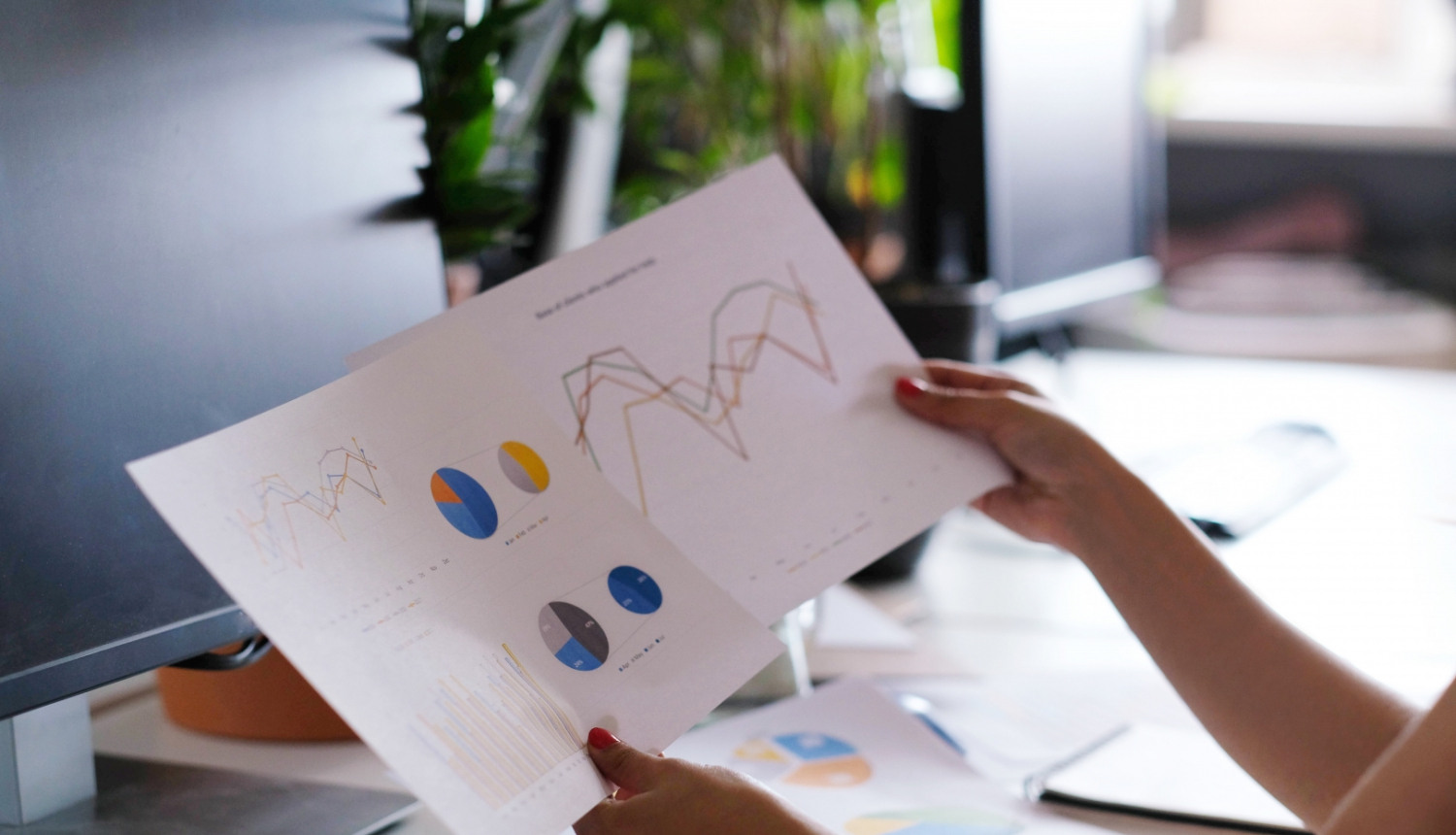 sieviete rokās tur divas lapas ar statistikas vizualizācijām